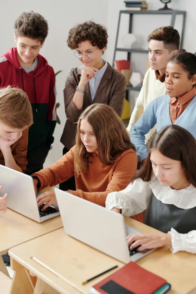 Enseignante et élèves travaillant sur ordinateurs portables