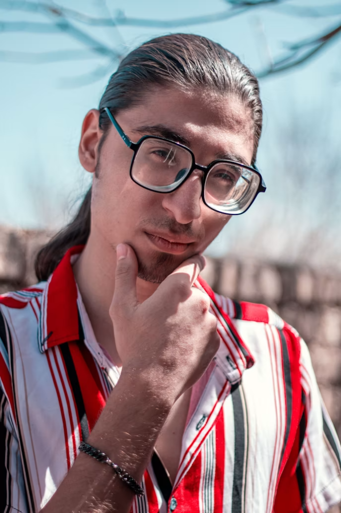 Homme pensif avec lunettes et chemise rayée rouge