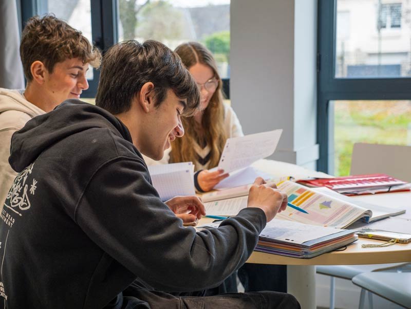 Trois étudiants révisant ensemble autour d’une table